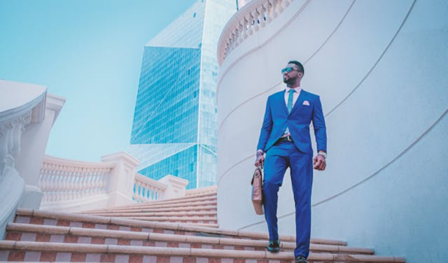 Confident professional in blue suit walking up stairs toward modern glass buildings, representing future career opportunities